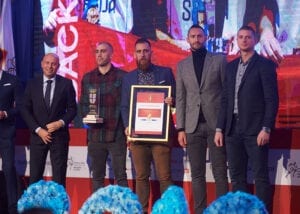 sportisti u odelima drze nagradu i pohvalnicu