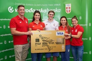 sportisti u crvenim majicama drze visa olimpijsku gold karticu